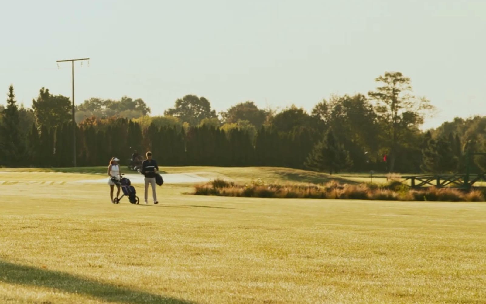 Two golfers walking a fairway together at golden hour